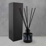 A round, 50ml black reed diffuser with five black sticks, presented beside a sleek black box.