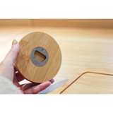 A drink bottle opener made from bamboo, featuring a round design and a metal bottle opener embedded in the centre.