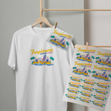 A white t-shirt features a colorful design with palm trees and beach elements, alongside printed transfer sheets on display.