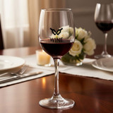 A wine glass with a round bowl, stem, and a logo, featuring red wine and placed elegantly on a table.