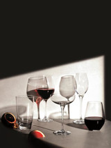 A collection of elegant glass wine glasses in various shapes, featuring red wine, on a softly lit surface.