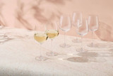 A set of six clear glass wine glasses, with two filled with white wine, arranged on a light surface.