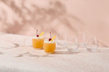 A set of six clear glass whisky glasses beside two cocktails topped with cherries and orange slices on a marble surface.