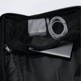 A black Eiger backpack interior featuring a metal device, tape, and a charging cable inside a mesh pocket.