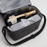 A cooler bag in grey, containing a bottle of champagne and a blanket, with a shoulder strap and a front pocket.