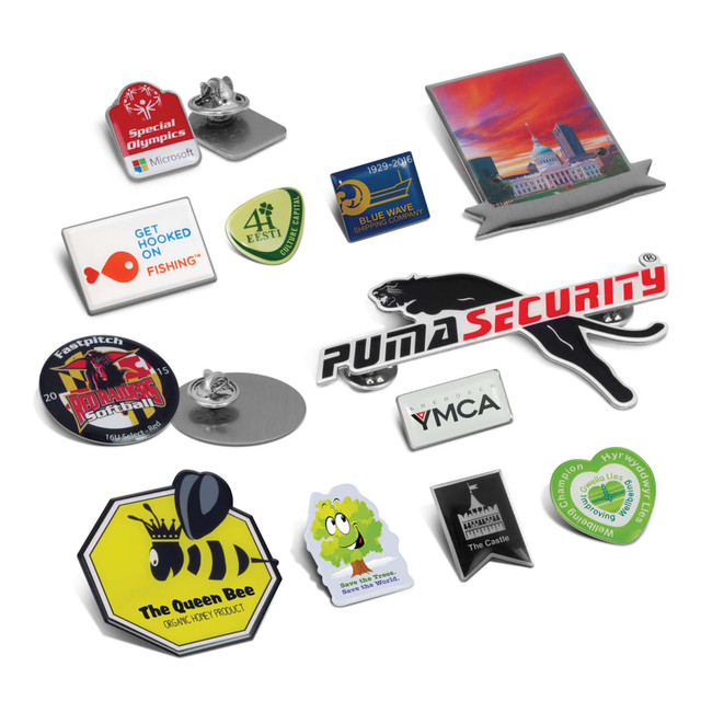 A collection of colourful lapel badges in various shapes, including animal, logo, and event-themed designs, with pins.