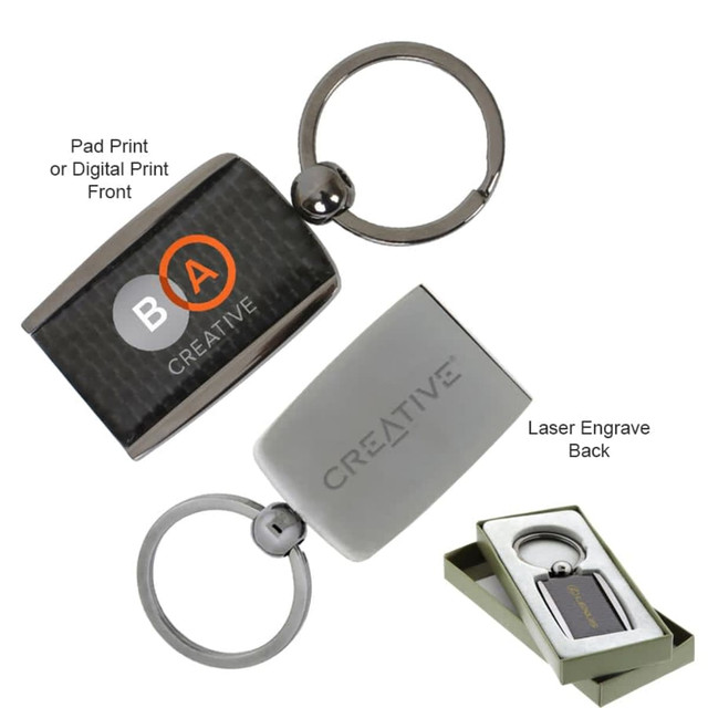 A carbon fibre keychain featuring a circular metal ring and a rectangular holder in silver and black, displayed in a gift box.