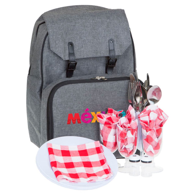 A grey picnic backpack with cutlery, plates, and checkered napkins displayed in front. The backpack features a logo.