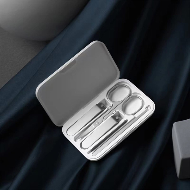 A manicure set with silver metal tools, housed in a sleek white case.