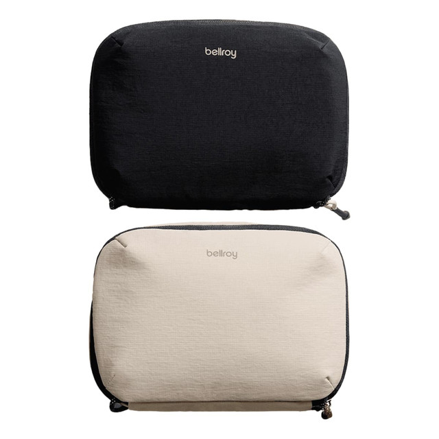 A black and a beige tech kit with zippers, both featuring a logo on the front.