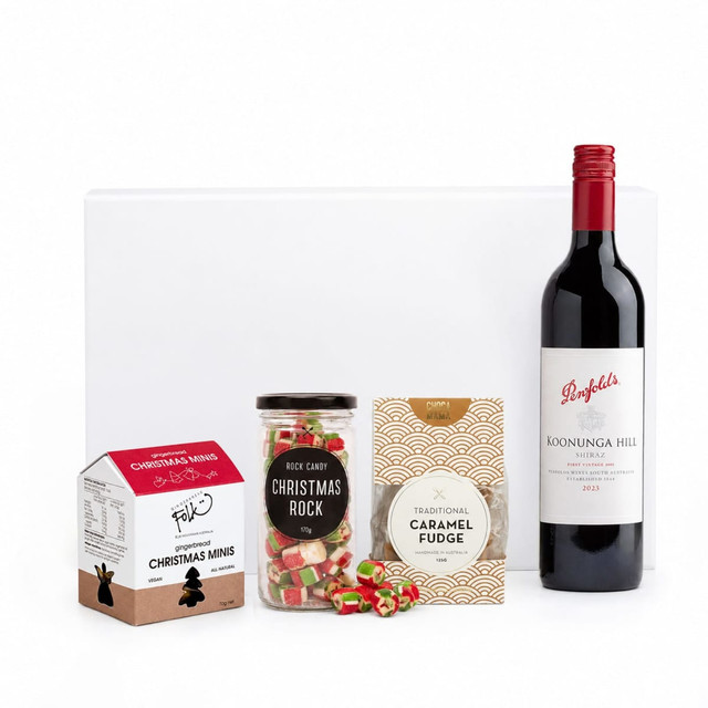 A drink bottle of red wine alongside Christmas-themed sweets: fudge, rock candy, and chocolate minis.