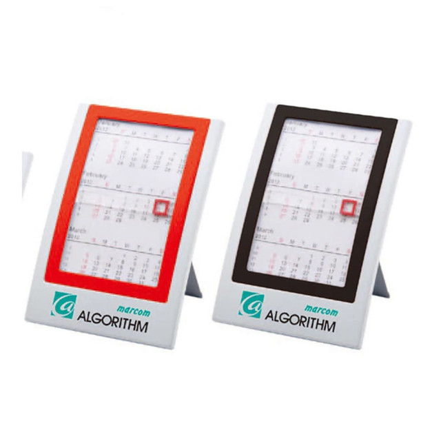 Two wall calendars displayed in a stand, one with a red frame and the other with a black frame, both featuring printed calendar pages. Two wall calendars displayed in a stand, one with a red frame and the other with a black frame, both featuring printed calendar pages.