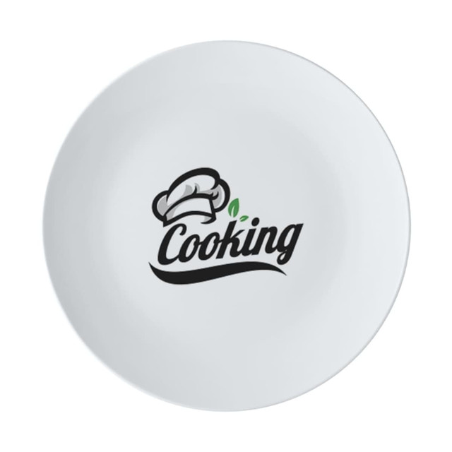 A white coupe dinner plate with a black logo featuring a chef's hat and the word "Cooking."