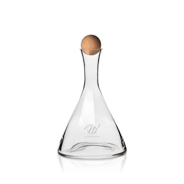 A glass wine decanter with a clear finish and a beechwood stopper, featuring a logo on its body.