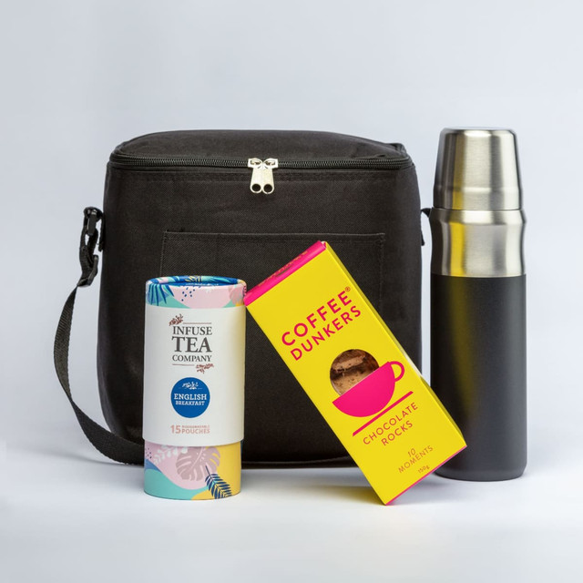 A drink bottle in black with a silver lid, alongside a tea canister and a box of chocolate snacks, all in a black bag.