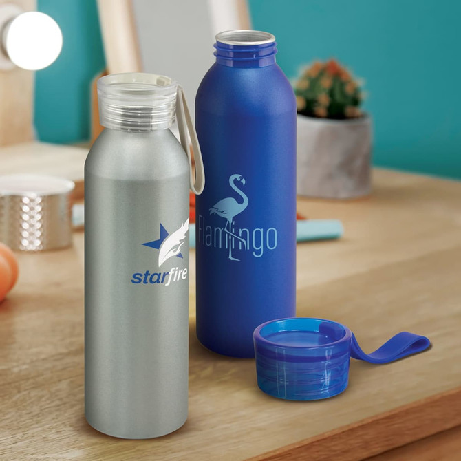 A drink bottle in silver with a logo, a blue bottle featuring a logo, and a blue cap on a wooden surface.