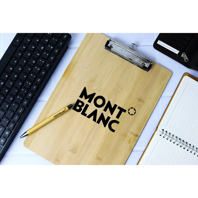 A bamboo clipboard with a metal clip and a logo, alongside a keyboard, pen, and notepad.