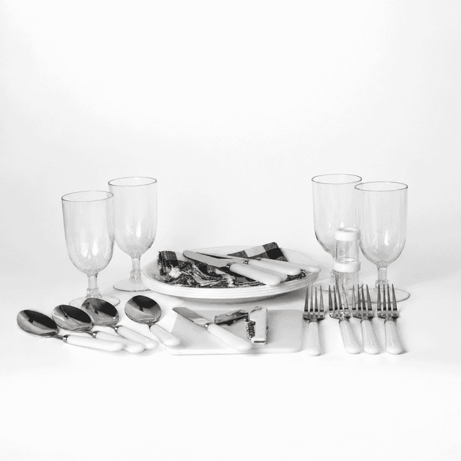 A picnic set features white-handled cutlery, glass tumblers, and serving platters on a white background.