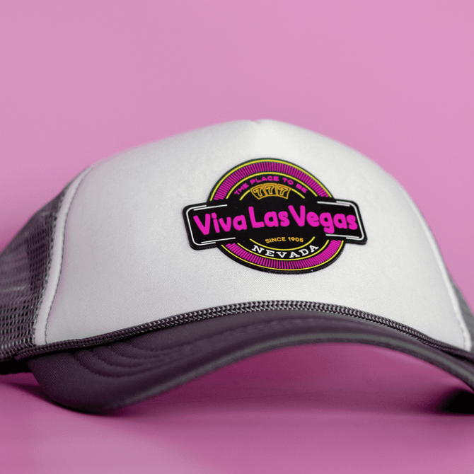 A grey and white cap featuring a round logo with vibrant pink and black elements.