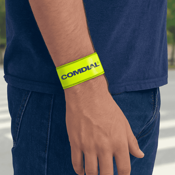 A reflective wristband in bright yellow with a logo, worn on a person's wrist.