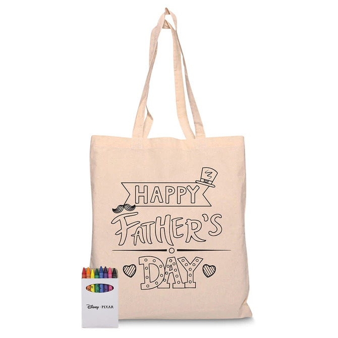 A beige tote bag featuring a black design for Father's Day, alongside a box of coloured crayons.