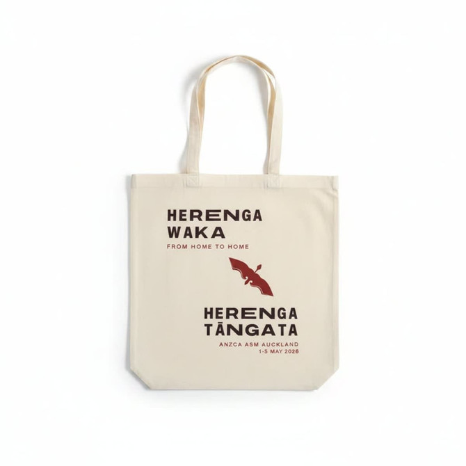 A cream tote bag with long handles featuring a logo, text, and a bat design in dark maroon.