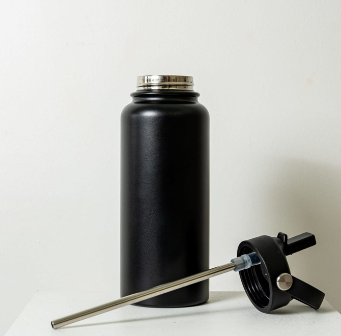 A drink bottle in matte black, featuring a removable lid and a stainless steel straw. It has a logo on the side.