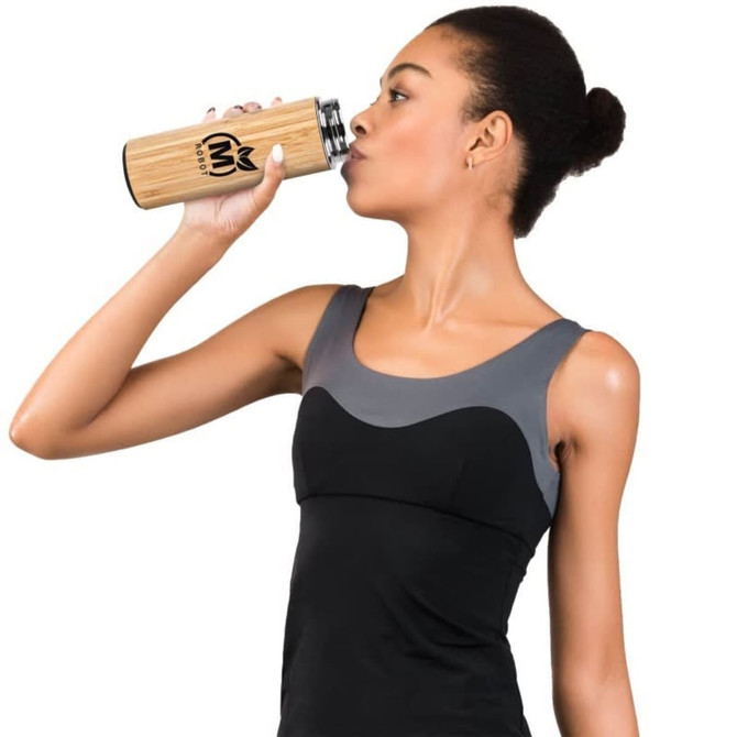 A drink bottle made of bamboo and stainless steel, featuring a logo, held by a person drinking from it.