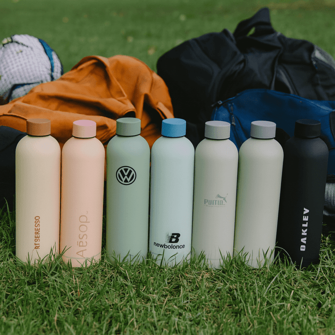 A row of drink bottles in various pastel colours, including peach, mint green, light blue, and black, with logos.