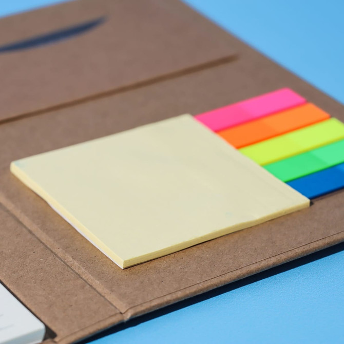 A brown notepad with a sticky note pad and colourful sticky flags in vibrant pink, green, and blue.