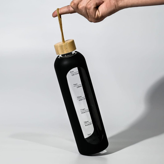 A drink bottle with a sleek black body and bamboo lid, featuring a built-in handle and measurement markings.