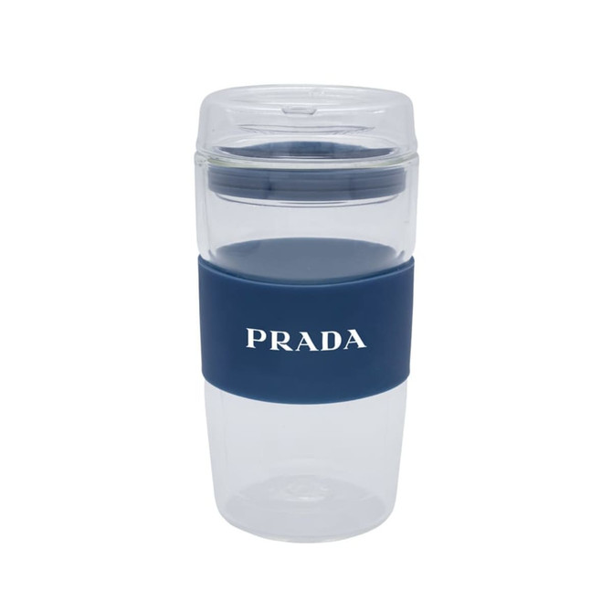 A reusable coffee cup in clear plastic with a navy silicone band and branding.