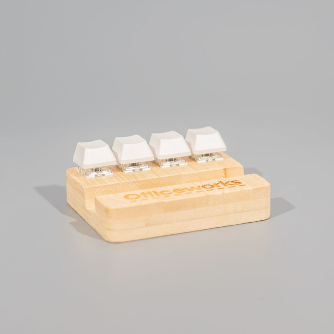 A bamboo stand holder featuring four white key-shaped stress relievers, with a logo on the base.