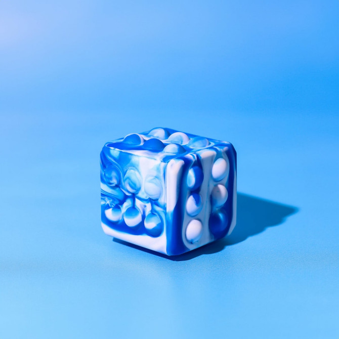 A blue and white Popper Cube with raised bubbles on its sides, set against a light blue background.