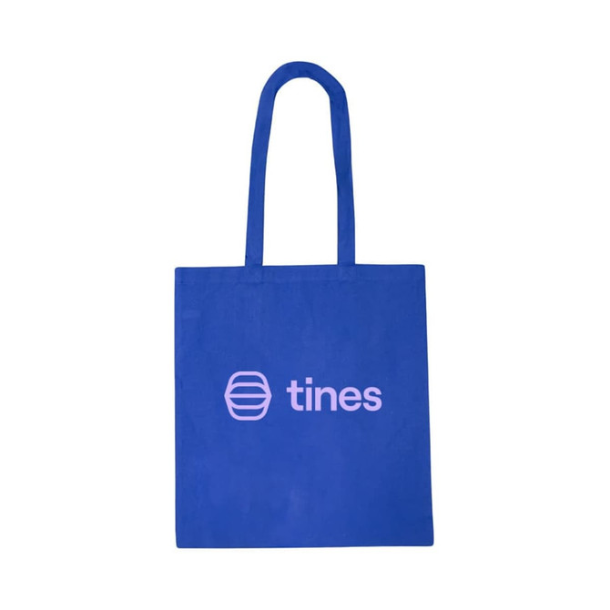 A vibrant blue cotton tote bag featuring a logo on one side. The bag has sturdy handles for easy carrying.