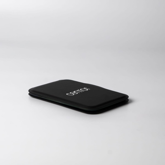 A black pocket mirror with a sleek, minimalist design, featuring a logo on its surface.
