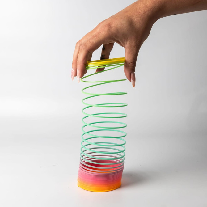 A drink bottle shaped like a spiral, featuring green, yellow, and gradient pink to orange colours. It has a logo.