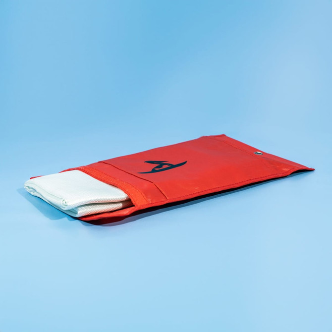 A red pouch containing a white fiberglass emergency fire blanket, featuring a logo.