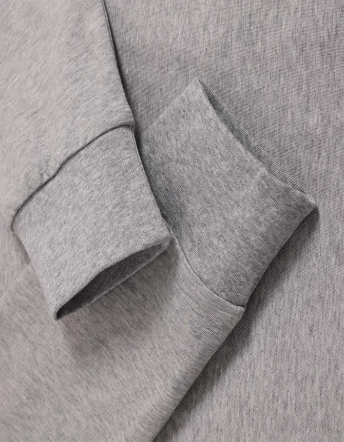 A grey long-sleeved cotton tee shirt featuring cuffed sleeves and a soft texture. It has a branding logo.
