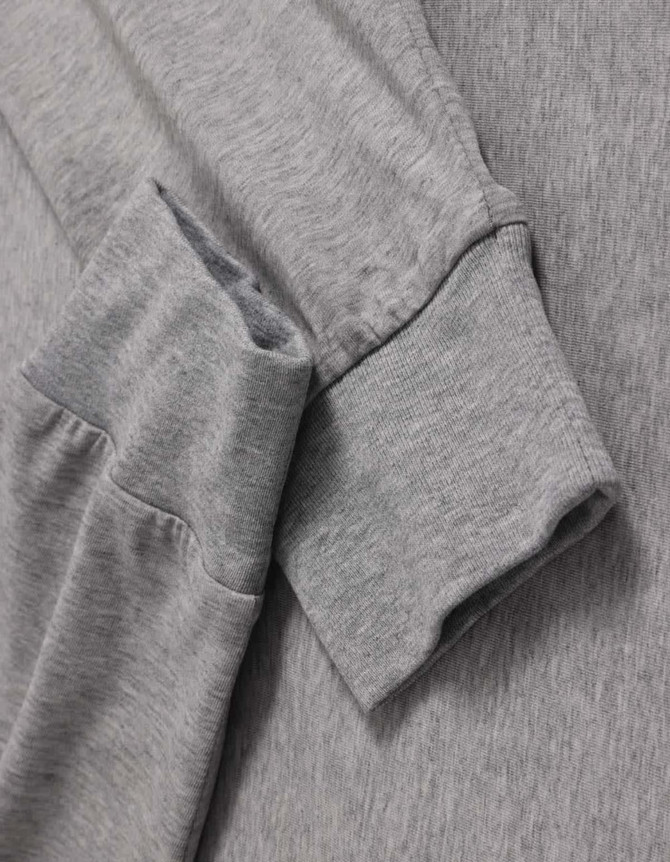 A grey long-sleeve tee shirt with a soft fabric and cuffed sleeves, featuring a logo on the side.