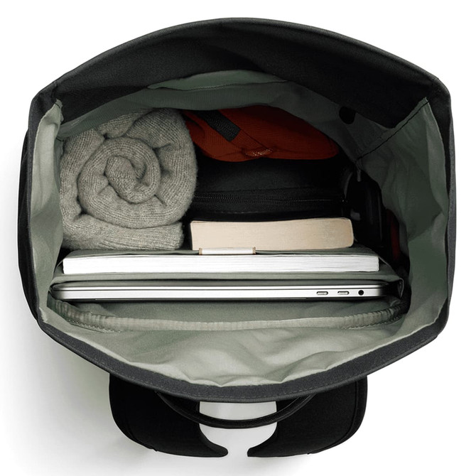 A black rolltop bag with a grey interior, containing a laptop, a book, and rolled clothing.