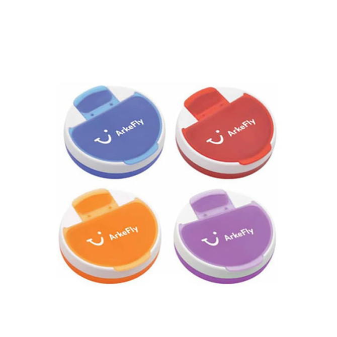 A set of four round pill boxes in blue, orange, red, and purple, each with a white lid and branding.