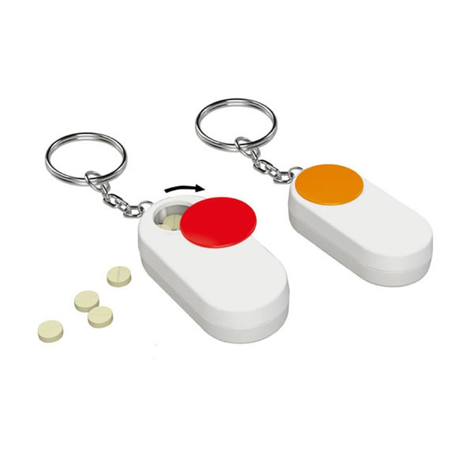 Two pill boxes in white with orange and red caps, accompanied by several small tablets on a surface. Each has a keychain attached.