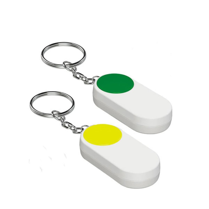 Two pill boxes in white with circular green and yellow buttons, attached to keychain rings.