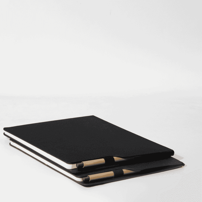 A black A4 notebook stacked with a pen, featuring a simple design and a logo on the cover.