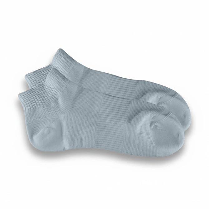 A pair of light blue ankle grip socks with a textured pattern and a ribbed cuff. Features a logo.