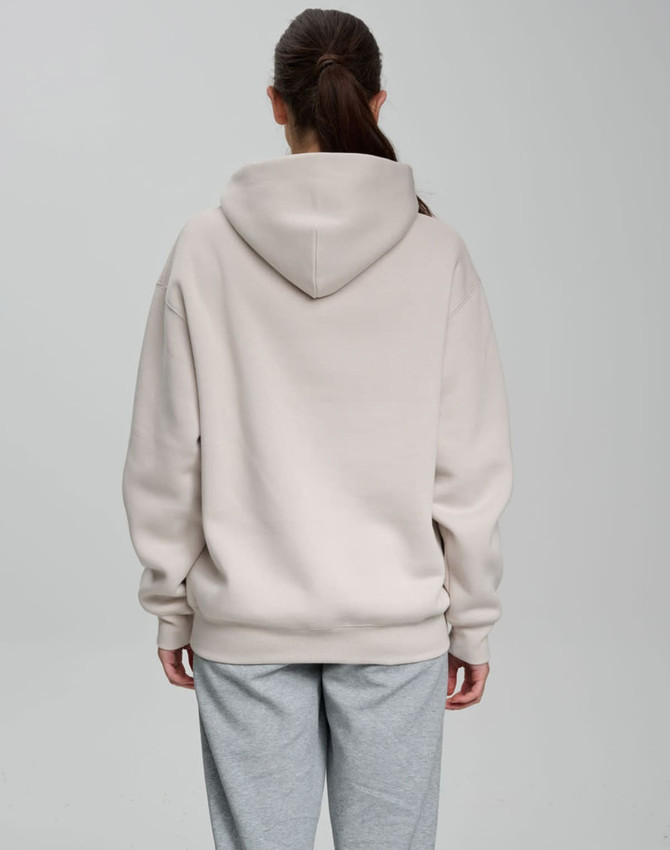 An oversized unisex hoodie in a light beige colour, featuring a spacious hood, shown from the back.