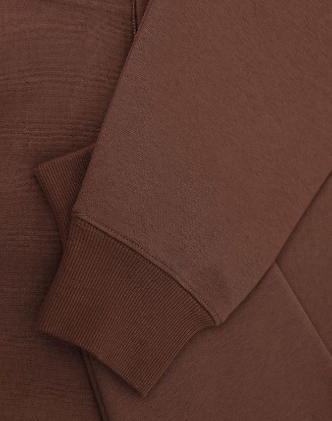 A brown unisex premium fleece oversized hoodie with ribbed cuffs and a soft finish. It features a logo.