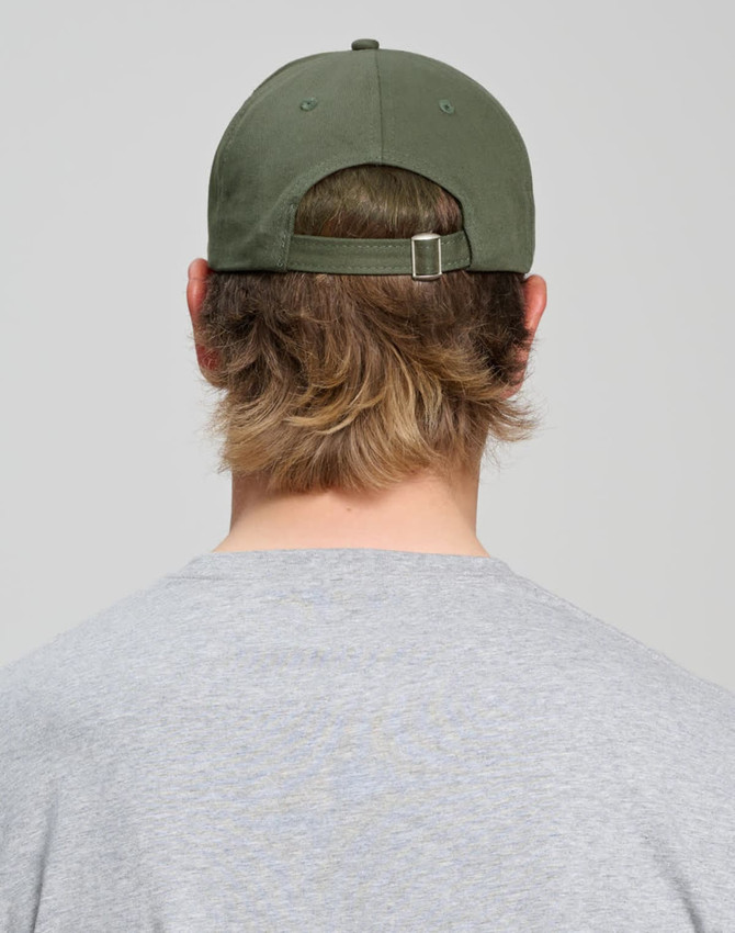 A cotton twill unstructured cap in olive green, viewed from the back, worn by a person with medium-length hair.