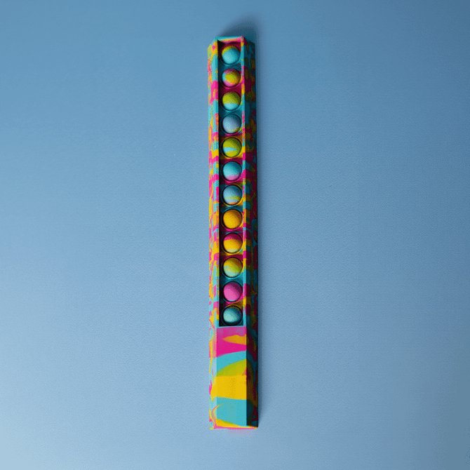 A colourful 30cm popper ruler with a vibrant design and multiple popping buttons along its length, featuring a logo.